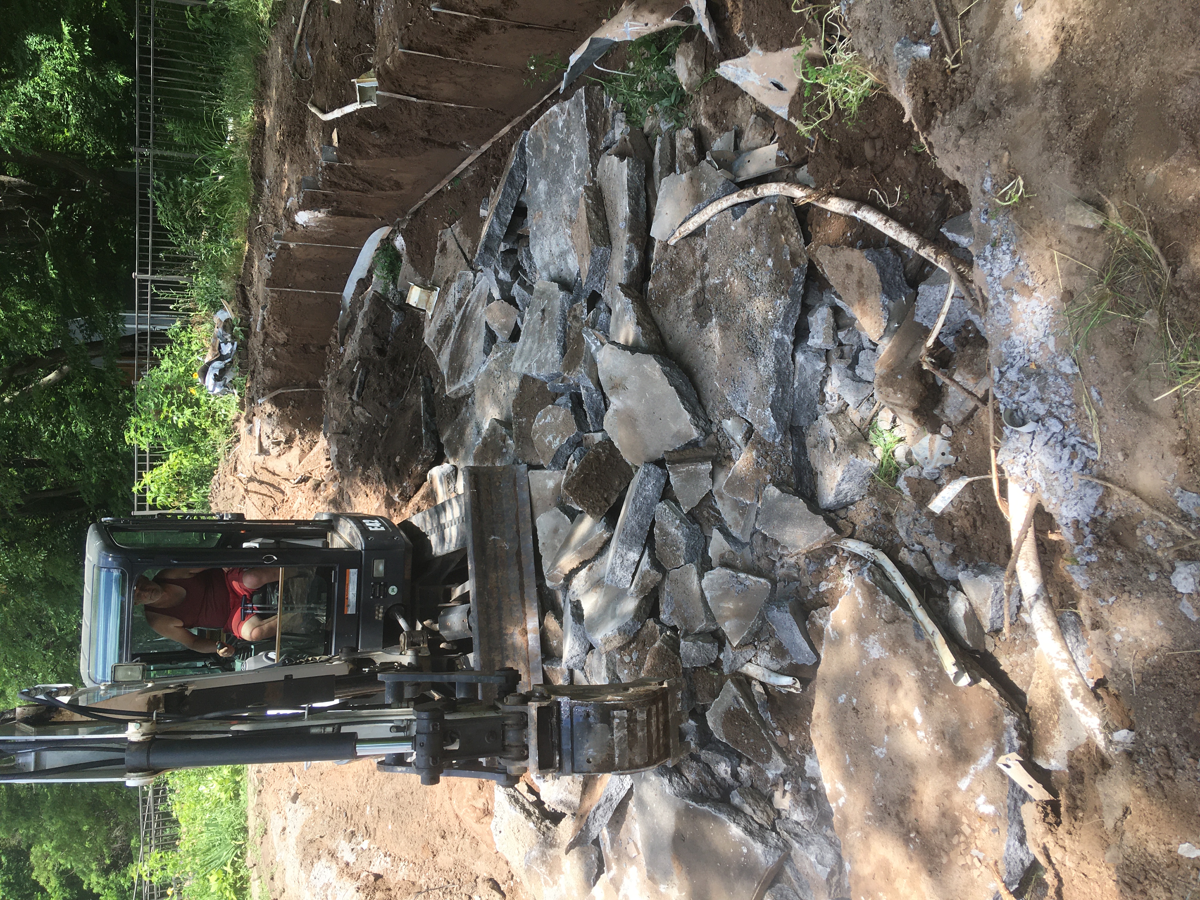 Excavator demolishing and removing an old swimming pool structure